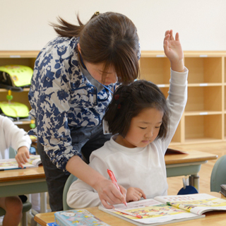 子どもの学習状況を確認する教師の写真