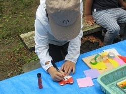 折り紙でつくった織姫の顔を描いている子ども