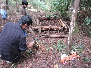 切った木の片方を尖らせている男性