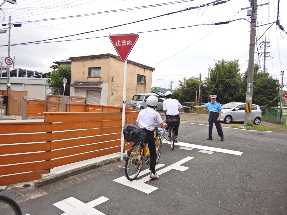 自転車通学する学生と交通指導員