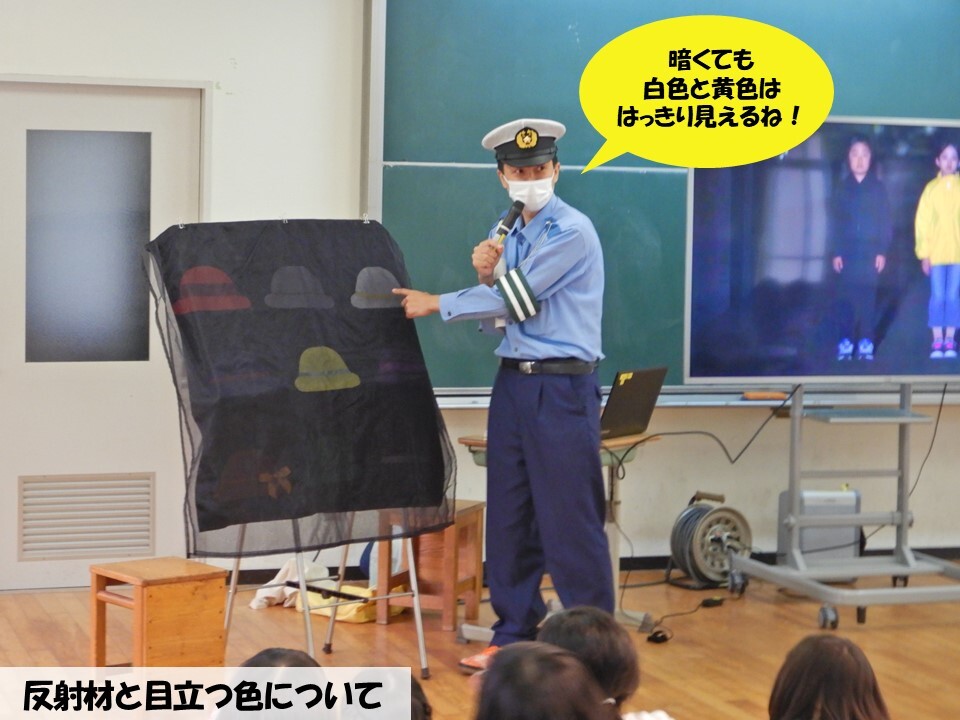 暗くても見えやすい色について帽子パネルで説明する警察官