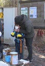 ヘルメットを母親に装着してもらっている男の子