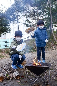 男の子2人がうちわで火おこししている写真