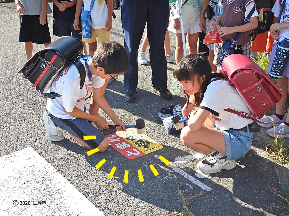 ストップマークの貼り換え作業をする小学生