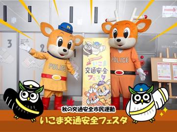 ナポナピが交通安全フェスタの看板の横で記念写真を撮っている